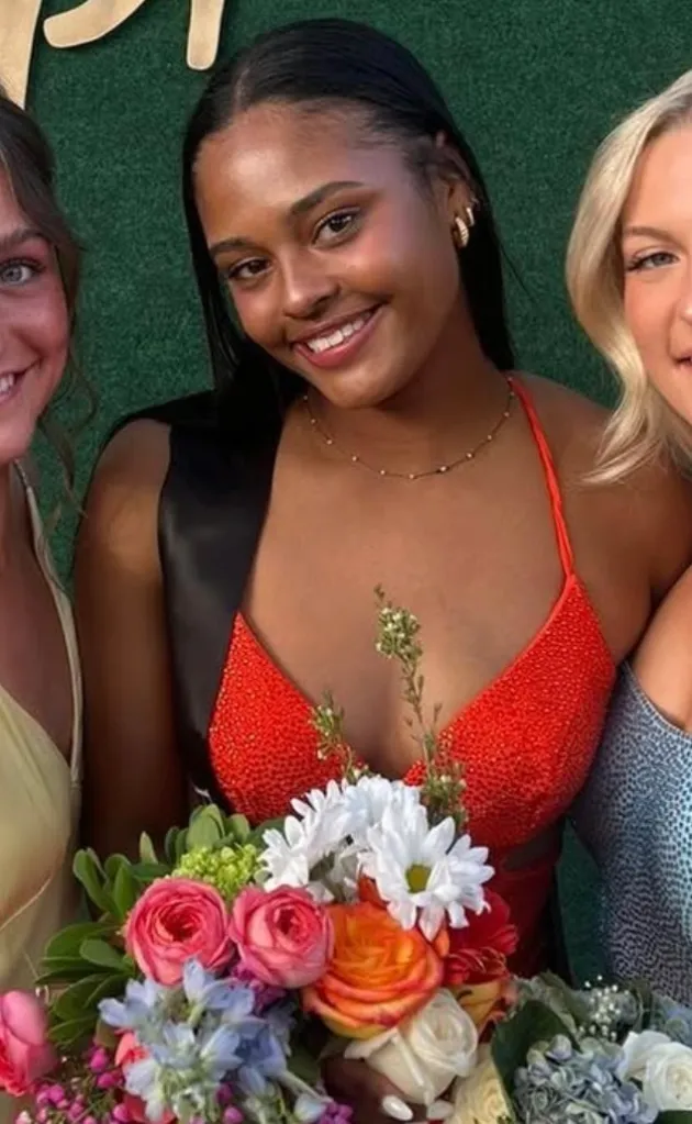 Sky Achola holding flowers while flanked by two other women.