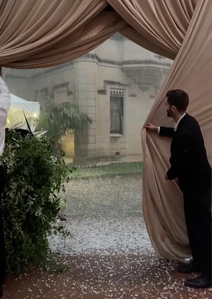 Wedding guests look outside at a severe hailstorm from a venue.