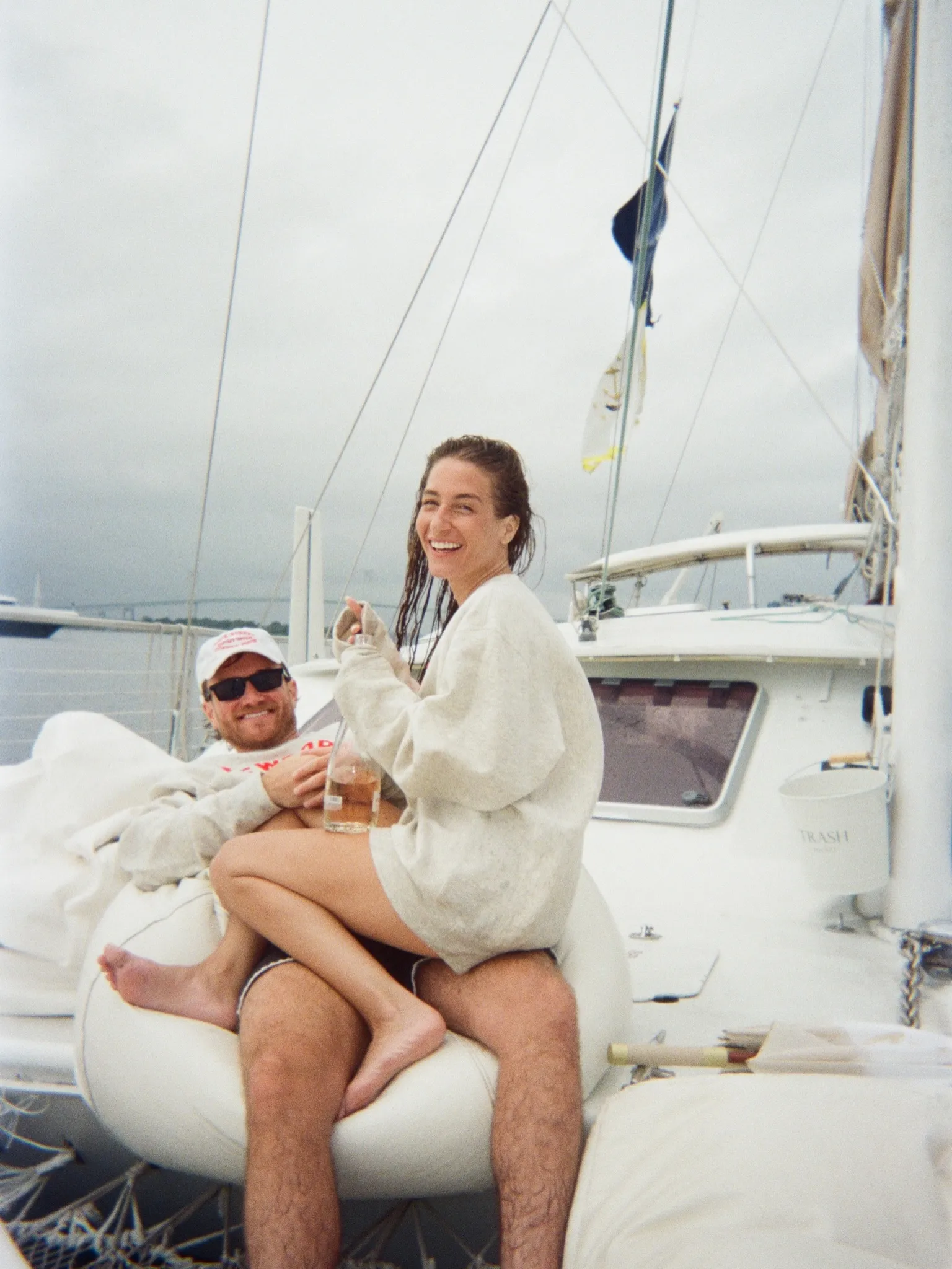 Amanda Batula and West Wilson relax on a sailboat, holding drinks and smiling.