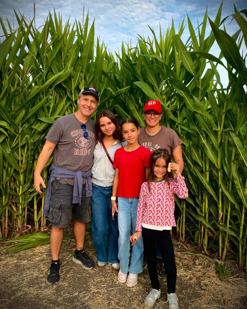 Chad Lowe with his wife Kim and daughters Mabel, Fiona, and Nixie standing in front of a cornfield.