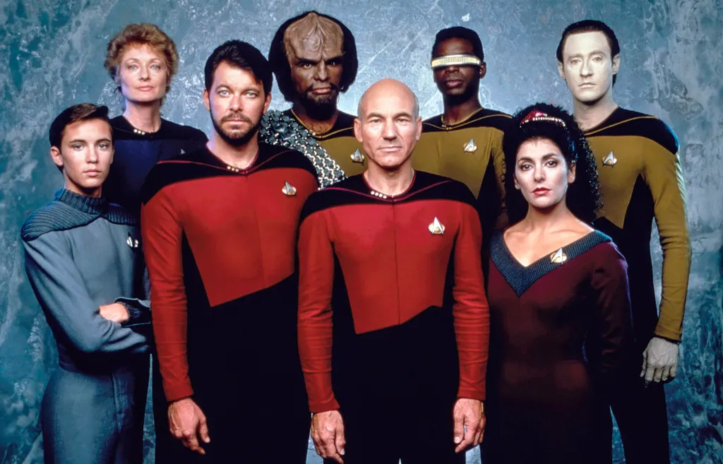 The cast of Star Trek: The Next Generation posing together, including Wil Wheaton, Diana Muldaur, Jonathan Frakes, Michael Dorn, Patrick Stewart, LeVar Burton, Marina Sirtis, and Brent Spiner.