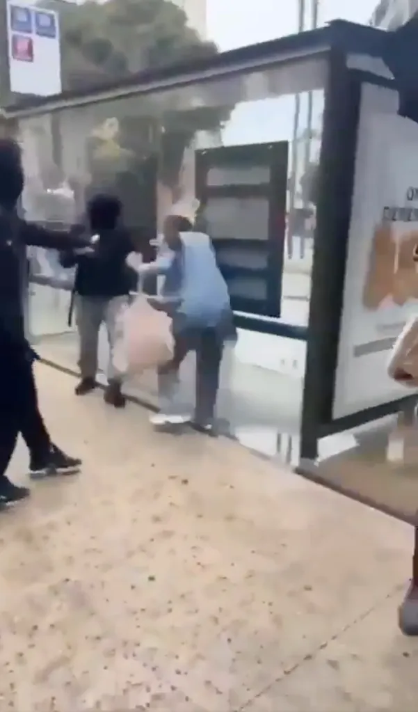A masked rioter attacks a woman with an improvised aerosol flamethrower near a bus shelter in Marseille.