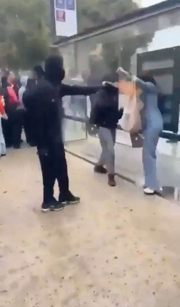 A masked, hooded rioter uses an improvised aerosol flamethrower against a woman in Marseille.