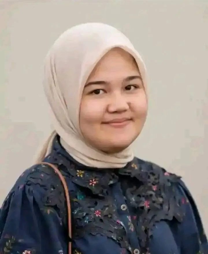 Portrait of Windy Rahma Putri wearing a cream-colored hijab and a dark blue patterned shirt.