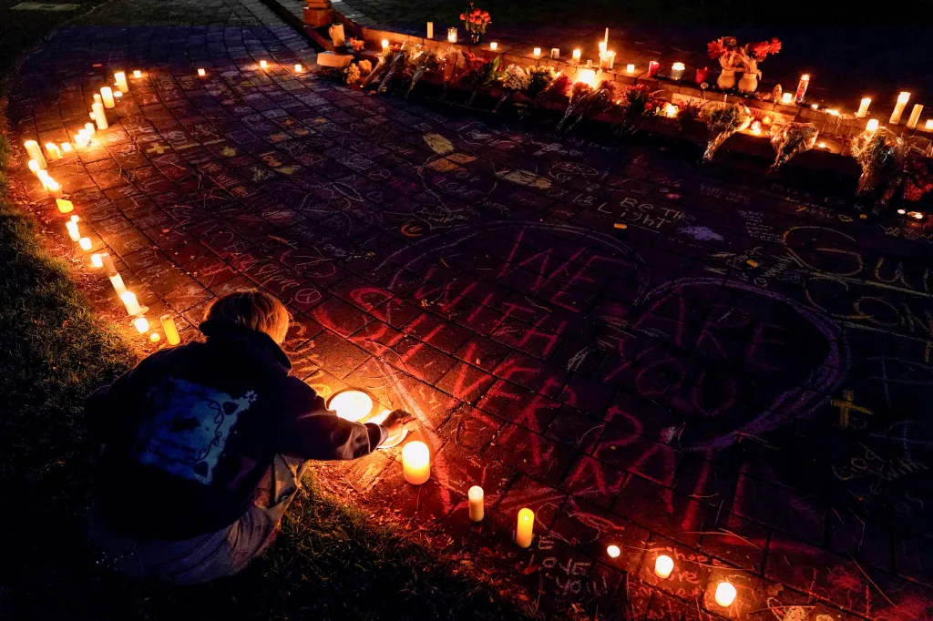A woman lights a candle during a candlelight vigil at Drake Park for victims of the Silver Rail Elementary School shooting.