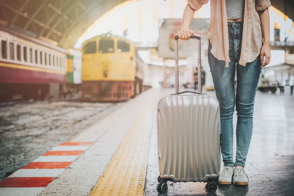 Woman traveler standing with luggage at train station.