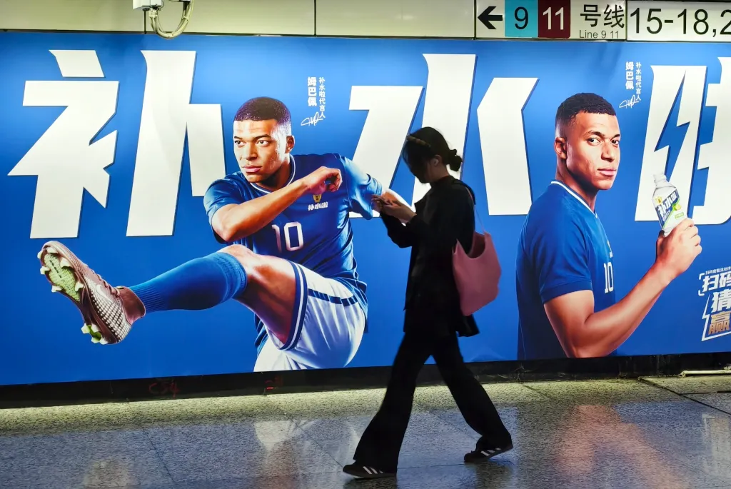 A woman walks past a large advertisement featuring French soccer player Kylian Mbappe.