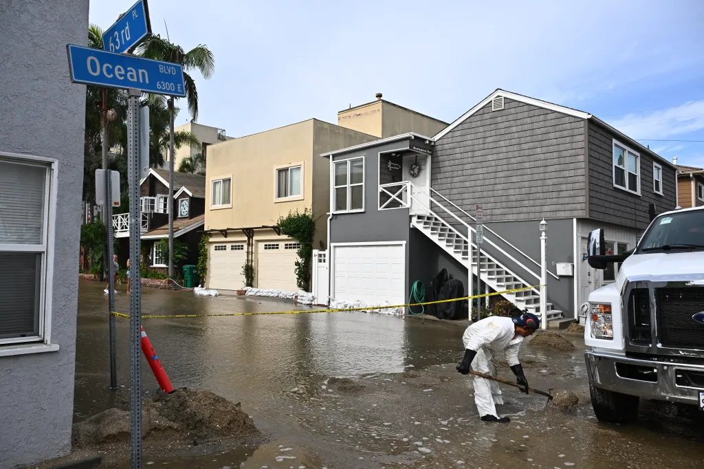 A worker clears debris from a flooded street in Long Beach, California.