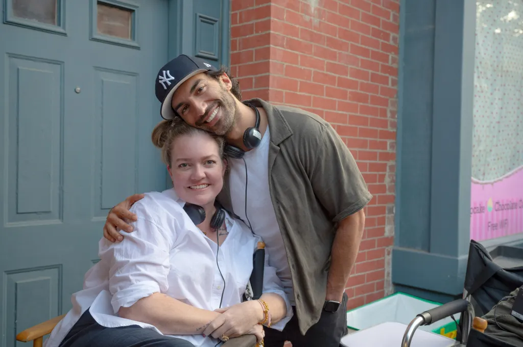 Writer Colleen Hoover and director Justin Baldoni posing together on set.