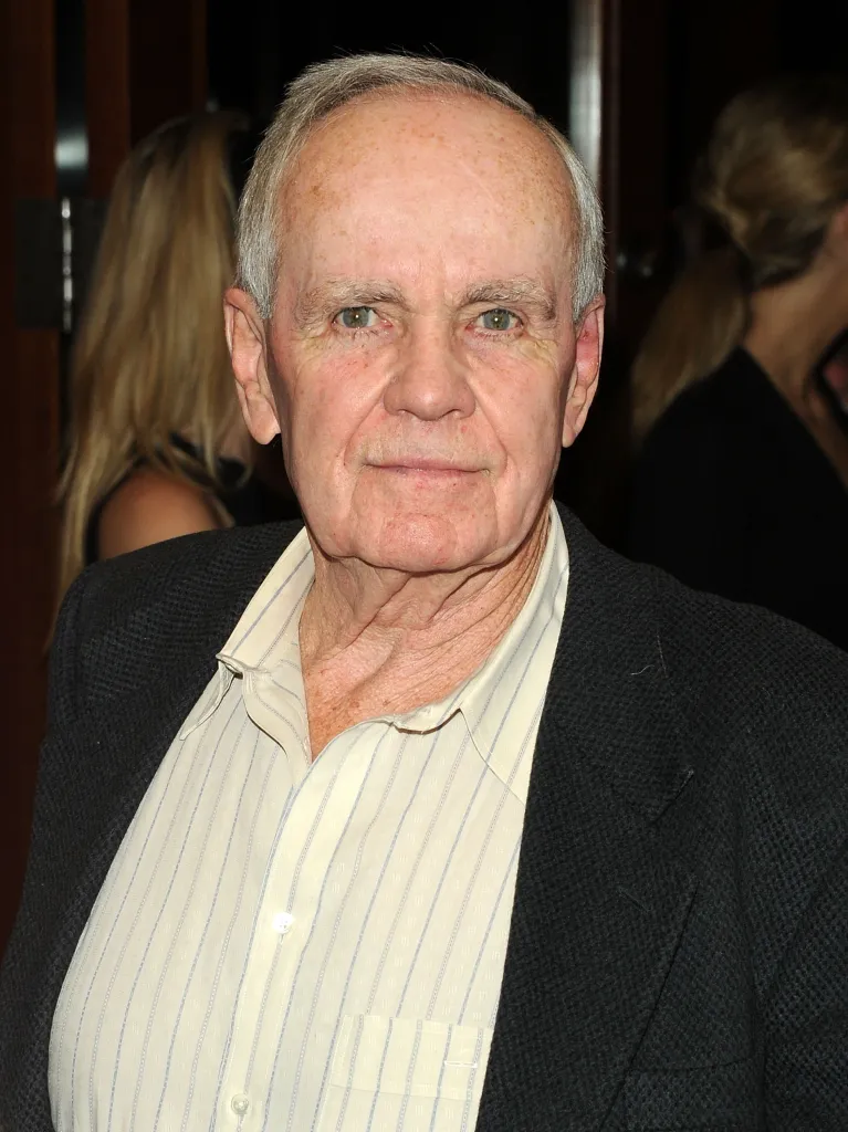 Writer Cormac McCarthy wearing a striped shirt and dark jacket.