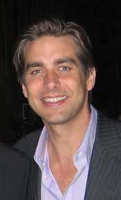 Jason Galanis smiling in a suit and light-colored shirt.