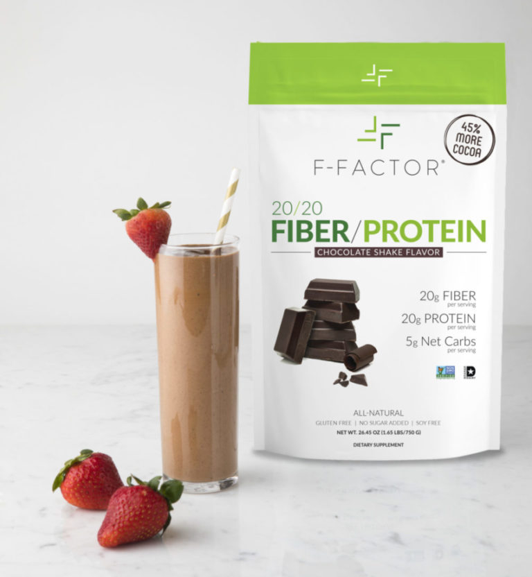 A pouch of F-Factor 20/20 Fiber/Protein chocolate shake powder alongside a glass of chocolate shake garnished with strawberries and a straw.