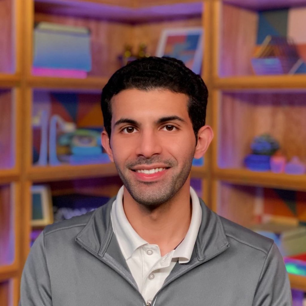 Portrait of Abdulrahman Alfozan, smiling in front of a bookshelf.