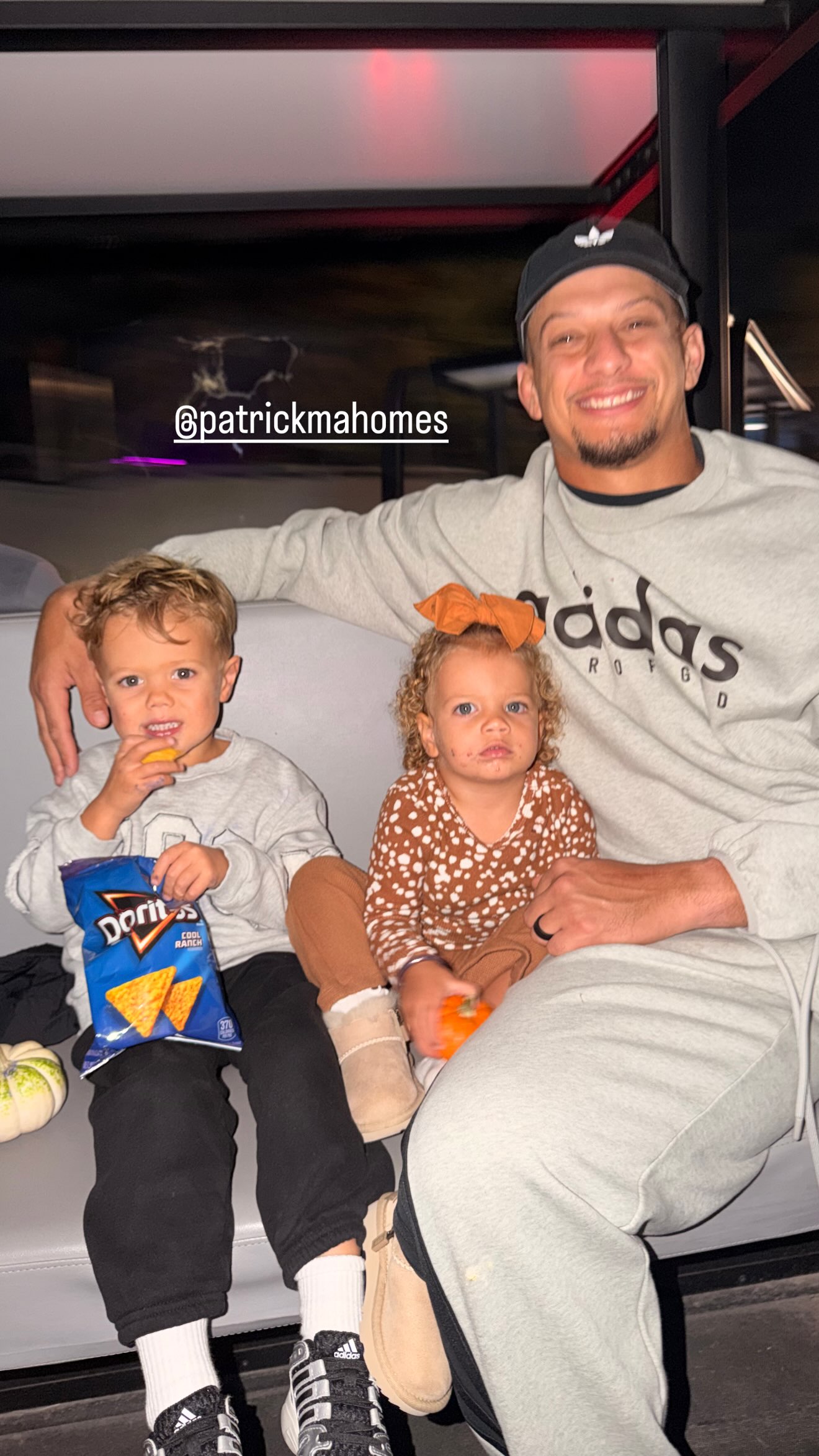 Patrick Mahomes sitting with his son eating Doritos and his daughter holding a small pumpkin.