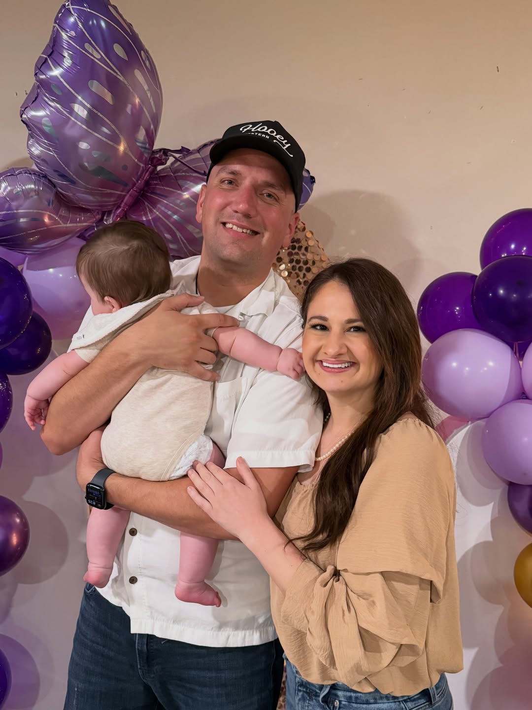 Gypsy Rose Blanchard and Ken Urker smiling together with a baby, surrounded by purple balloons.
