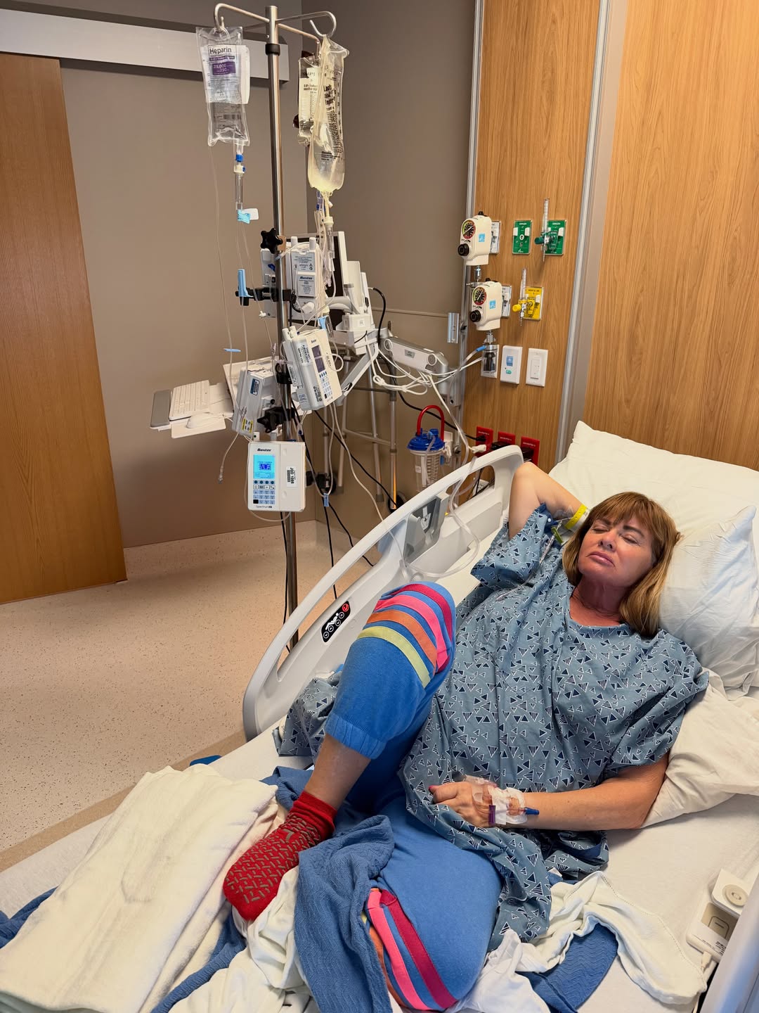 Jeana Keough lying in a hospital bed with an IV pole.