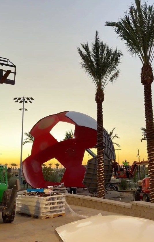 Construction of a giant soccer ball sculpture at Ontario Sports Empire during sunset.