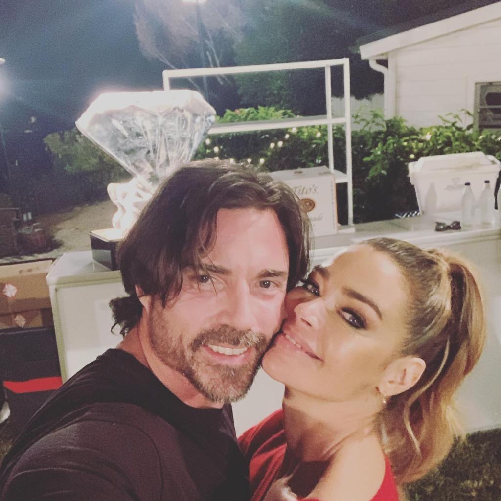 Denise Richards and Aaron Phypers posing for a selfie outdoors at night.