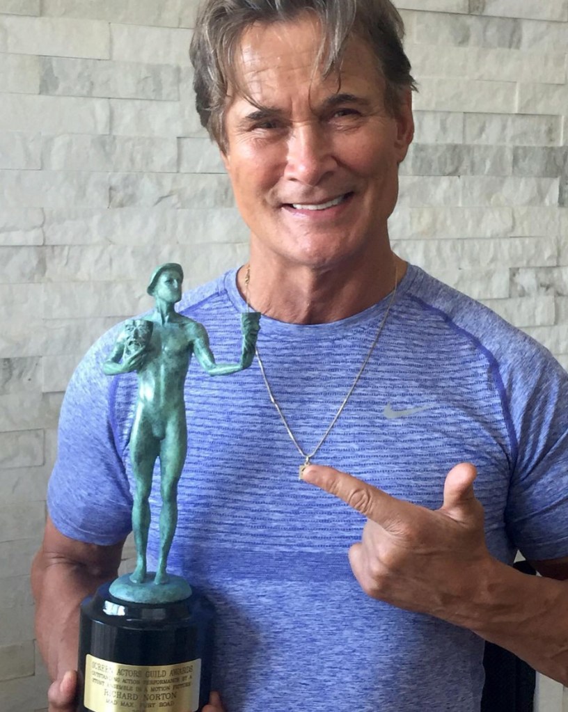 Richard Norton posing with a Screen Actors Guild Award.