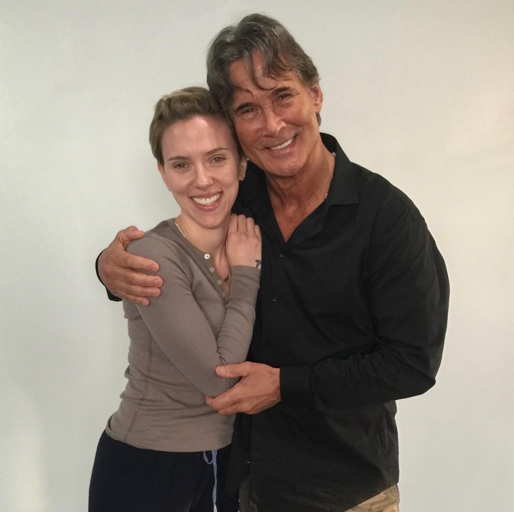 Richard Norton and Scarlett Johansson smiling while embracing each other.