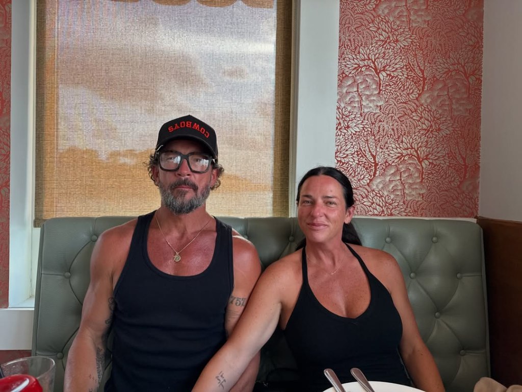 Carl Lentz and his wife, Laura, sitting together on a green leather booth.