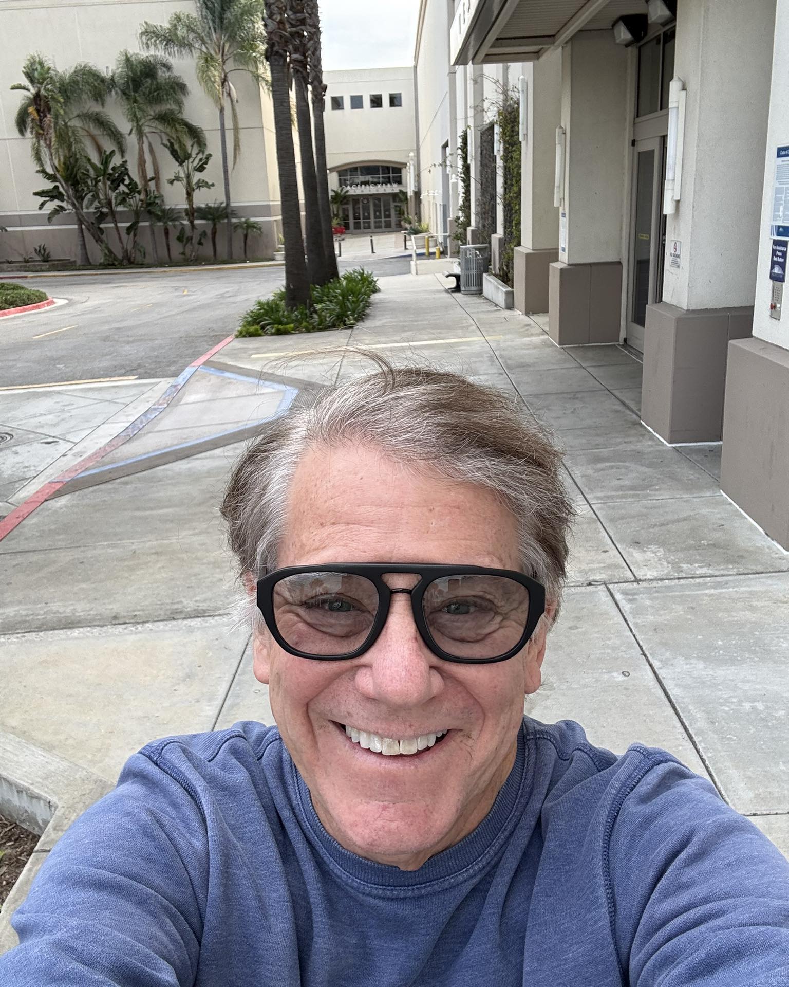 Anson Williams smiling for a selfie outside a commercial building.