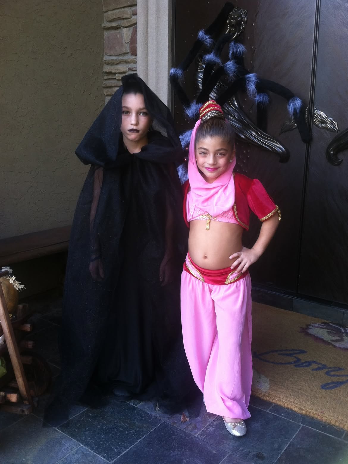 Two young girls in Halloween costumes posing for a photo.