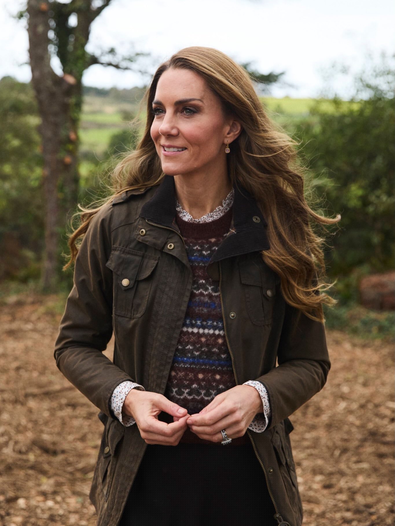 Kate Middleton wearing a dark green jacket and patterned sweater outdoors.