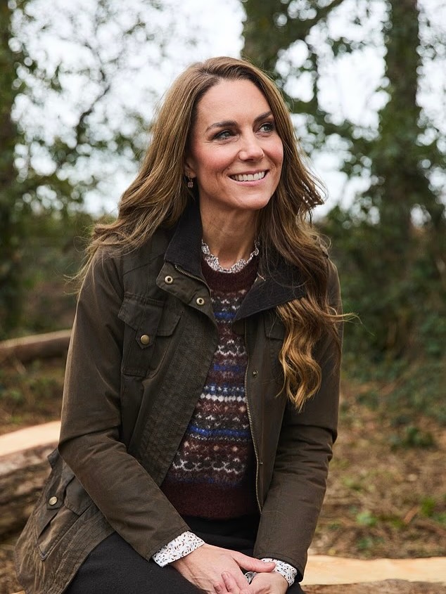 Kate Middleton smiling outdoors, wearing an olive green jacket and patterned sweater.