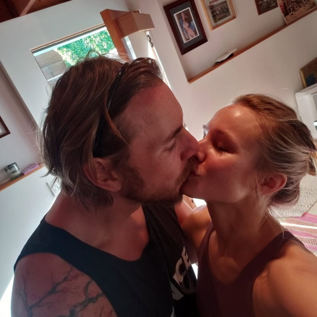 Kristen Bell and Dax Shepard kissing indoors.