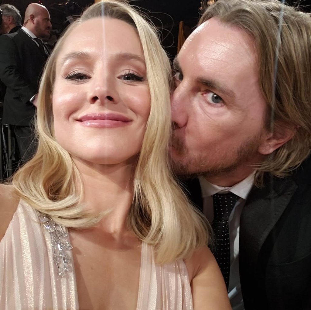 Kristen Bell smiling while Dax Shepard kisses her cheek.
