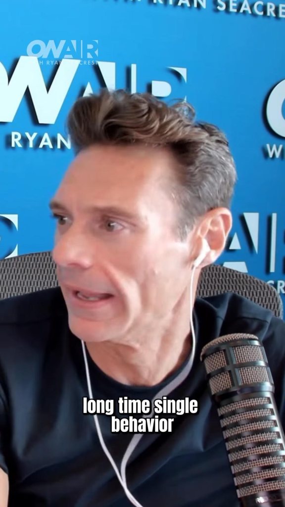 Ryan Seacrest speaking into a microphone in a studio.