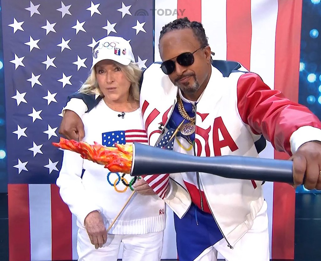 Martha Stewart and Snoop Dogg holding an Olympic torch in front of an American flag.