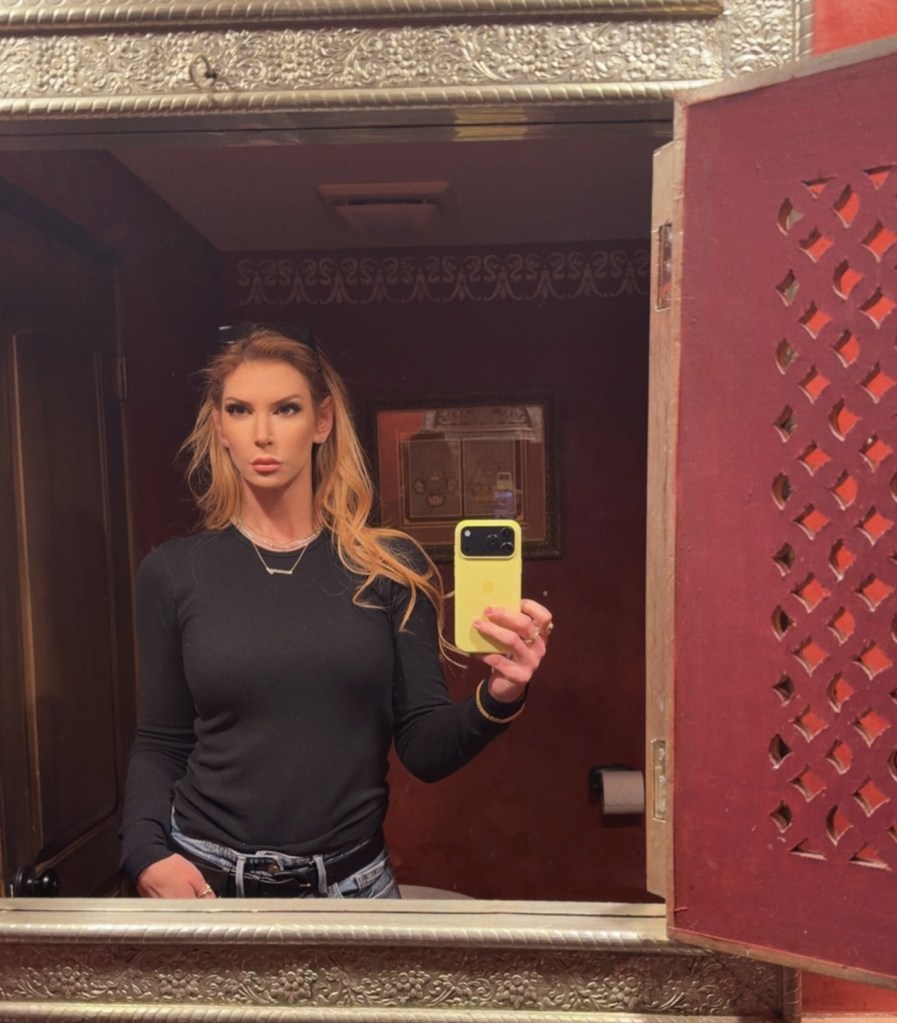 Lindsay Brooke takes a mirror selfie wearing a black long-sleeve shirt and jeans.