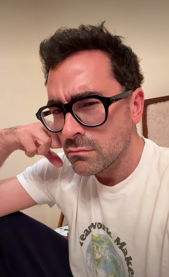 Dan Levy leaning on his hand with a displeased expression.