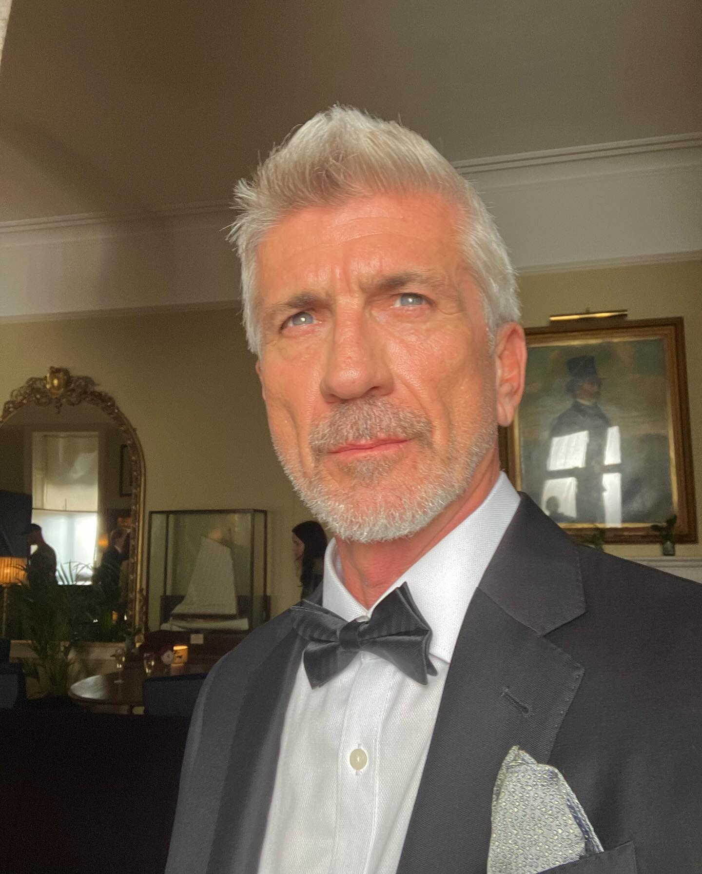 Joe Lando wearing a tuxedo and bow tie indoors.