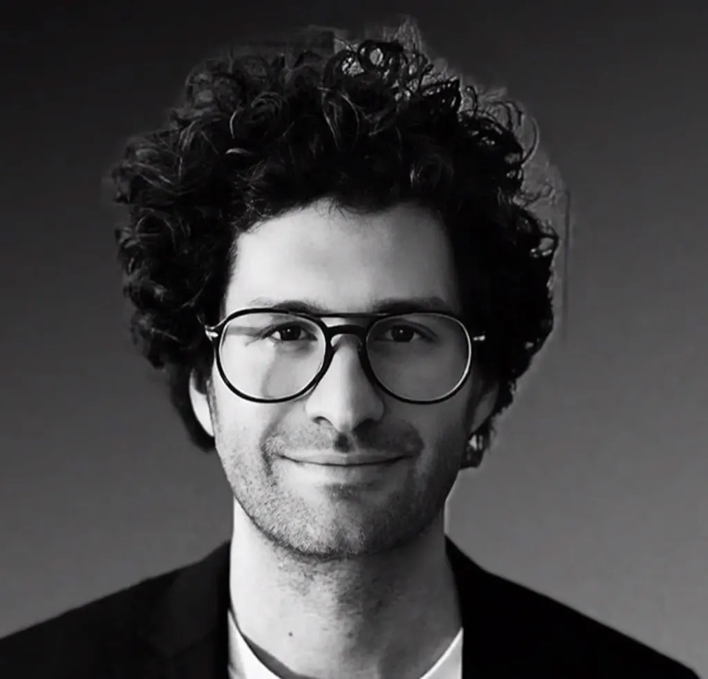 Black and white portrait of Austin Sosa with curly hair and glasses.