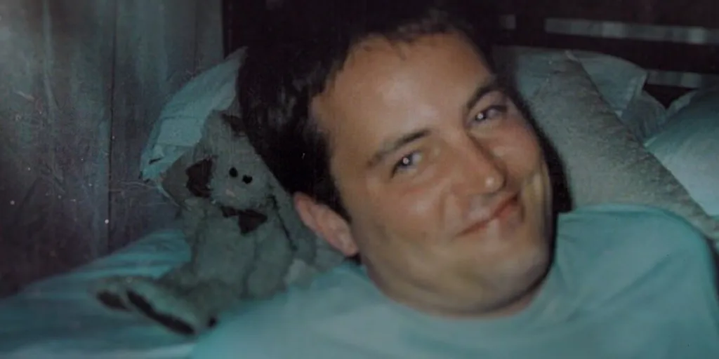 Matthew Perry lying in bed with a stuffed animal.