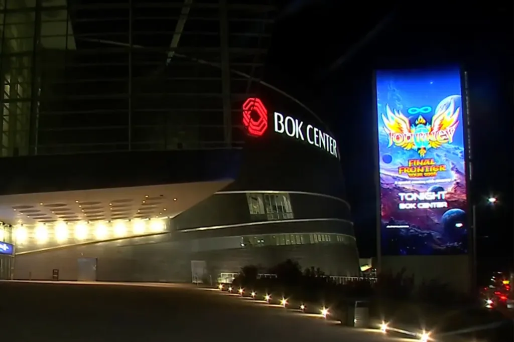The BOK Center at night, with a lit-up marquee advertising a Journey concert.