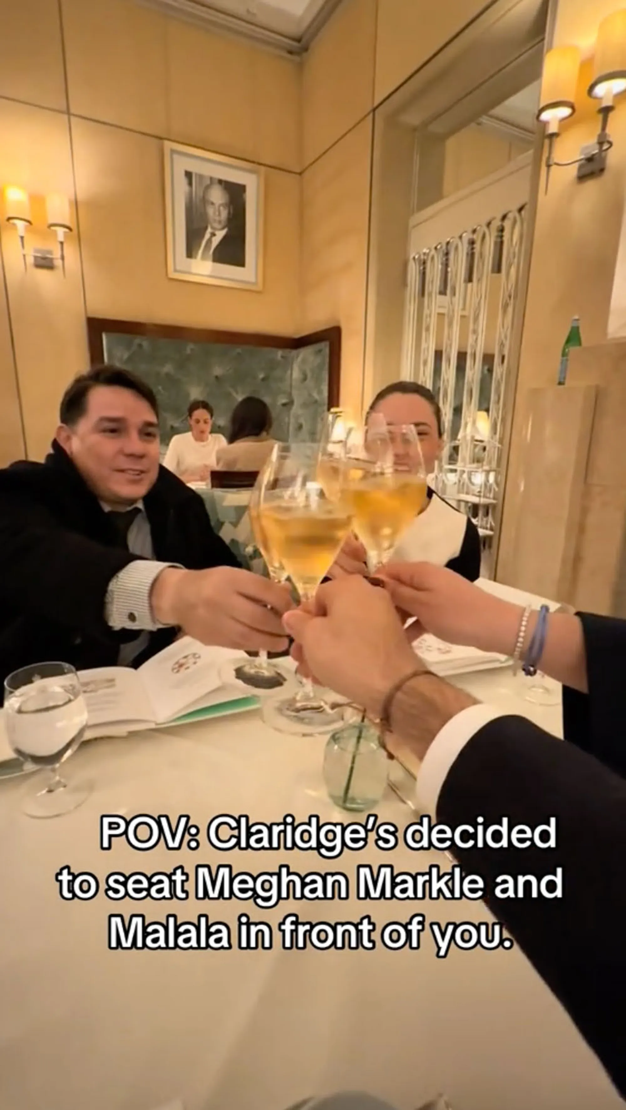 A group of people sitting at a restaurant table, clinking glasses with drinks, with a text overlay that reads 