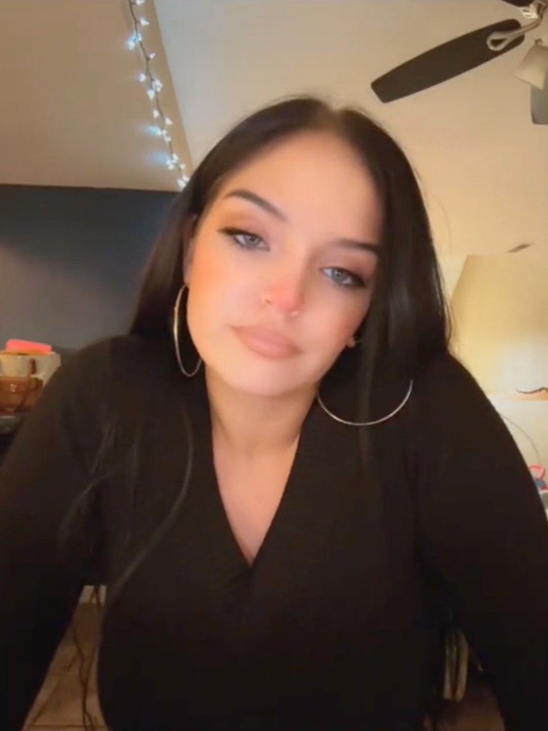 Autum Urker wearing a black V-neck top and large hoop earrings.