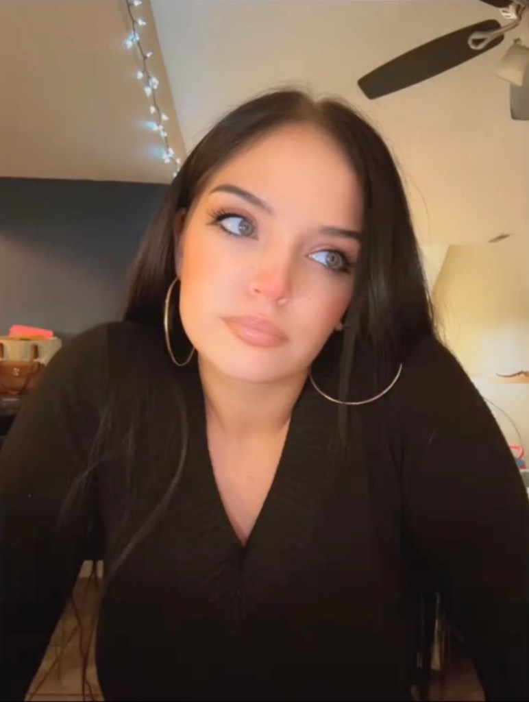 Autum Urker wearing a black V-neck top and large hoop earrings.