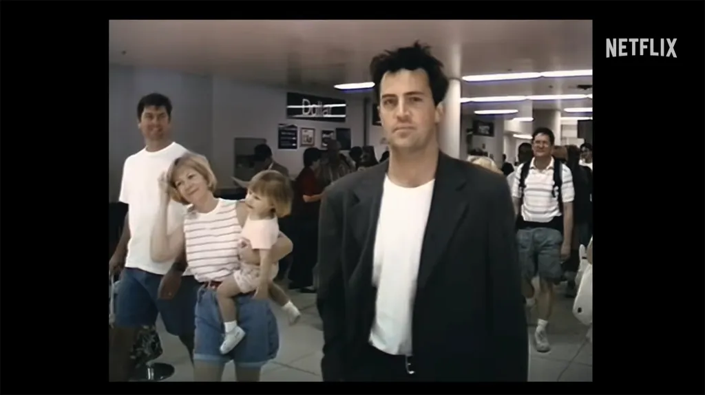 Matthew Perry walking through an airport terminal with other travelers.