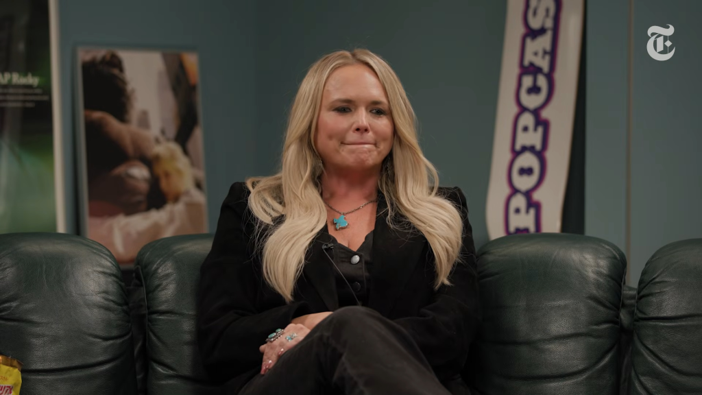 Miranda Lambert sitting on a green leather couch in an interview setting.
