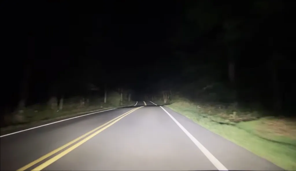 A dark, winding road illuminated by headlights at night on Clinton Road in New Jersey.