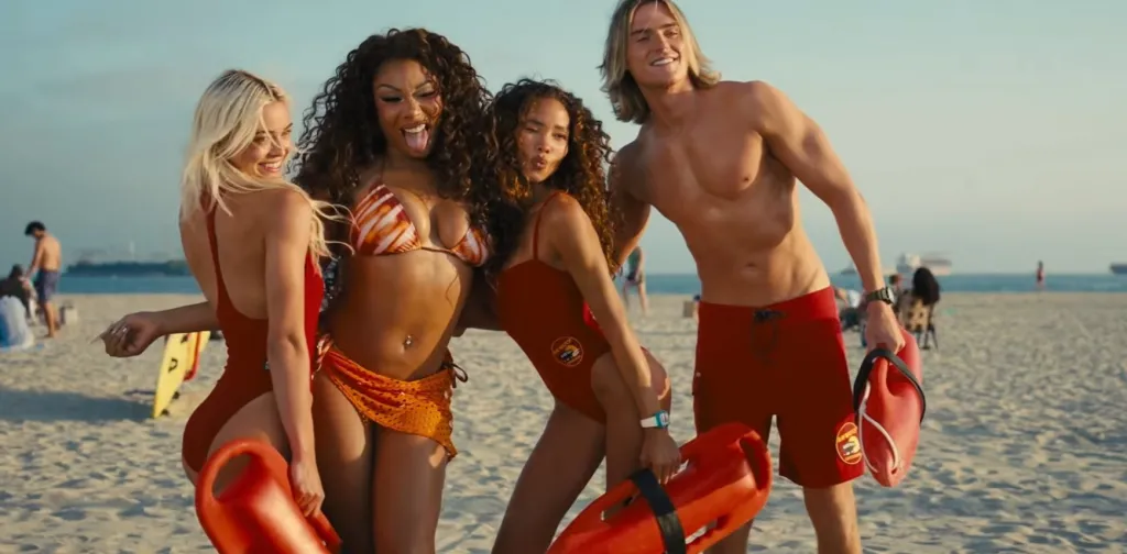 Four lifeguards on a beach holding rescue cans, posing for a photo.
