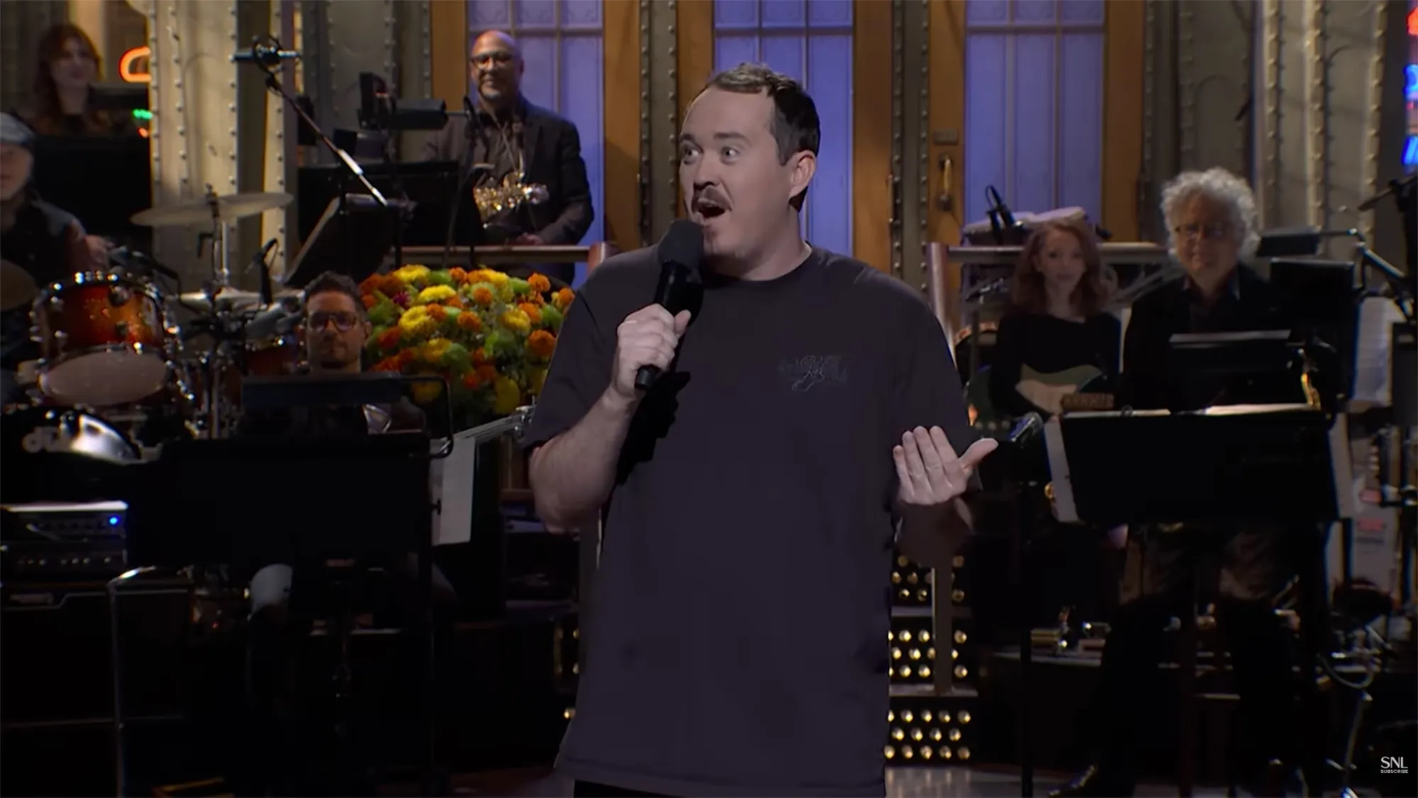Shane Gillis on stage with a microphone during his SNL monologue.