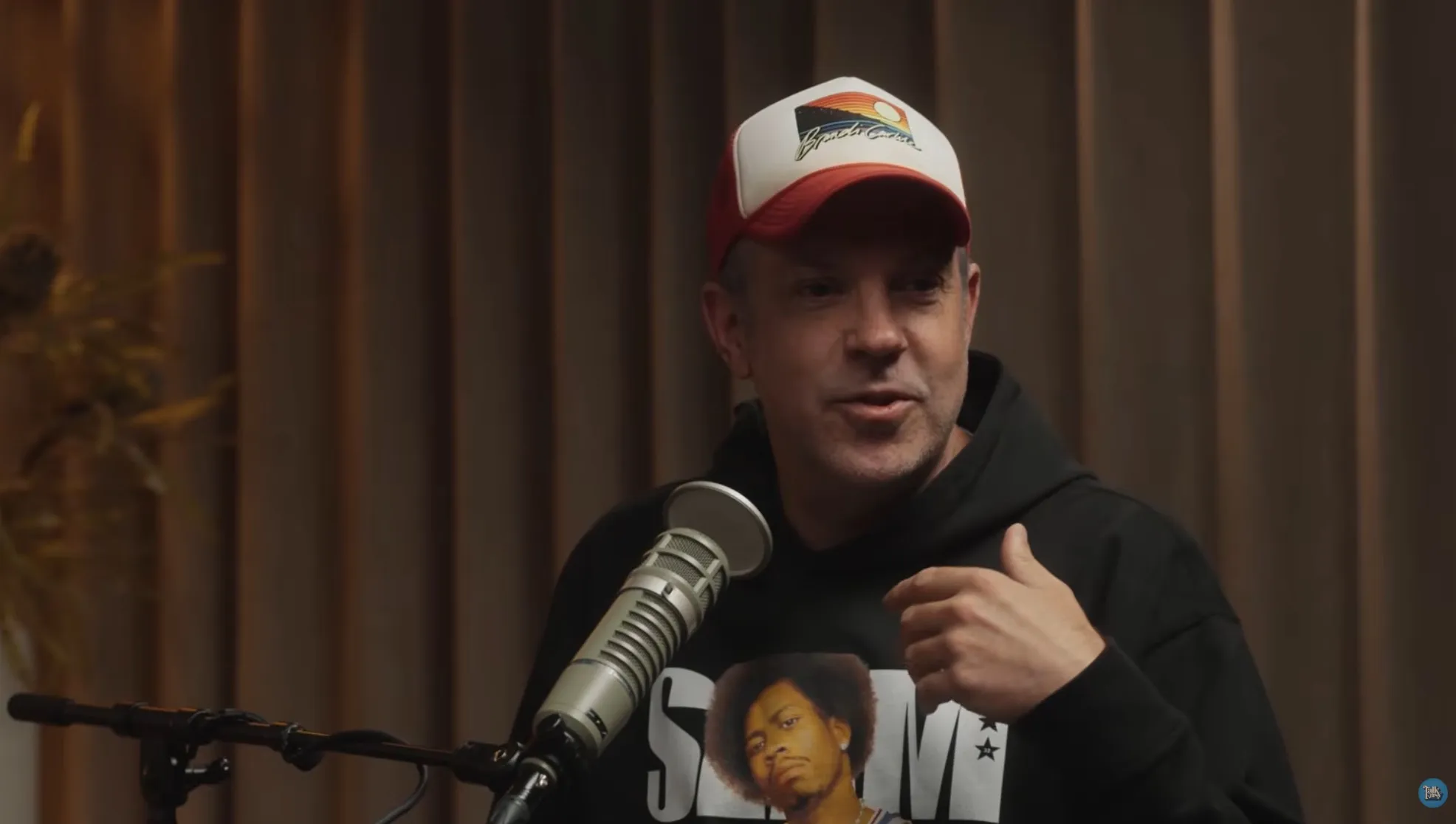 Jason Sudeikis in a studio speaking into a microphone.
