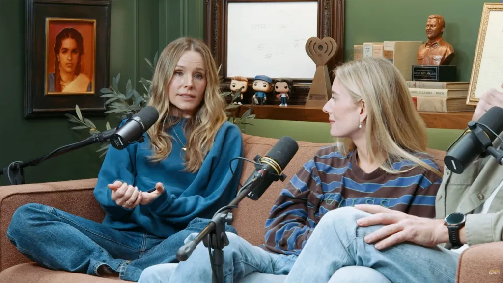 Kristen Bell sitting on a couch on a podcast set.