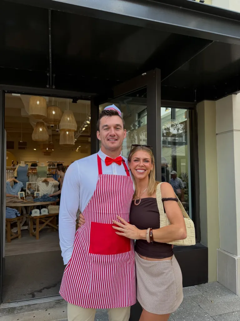 Tyler Cameron and fiancée Tate Madden standing together outside a storefront.